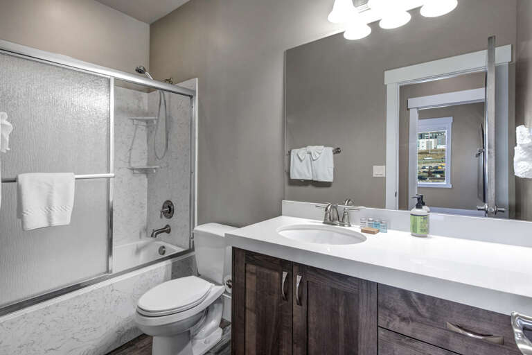 Step into your private bathroom, featuring a sleek walk-in shower, modern vanity with ample storage, and crisp white linens ready for your arrival.