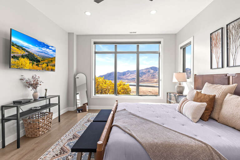 Sink into plush bedding and wake up to sweeping mountain views through expansive windows. Your serene retreat features modern decor, a wall-mounted TV, and all the comforts of home.