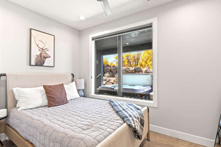 Step into your serene bedroom retreat with a plush queen bed and direct access to your private hot tub surrounded by golden autumn foliage and natural rock formations.