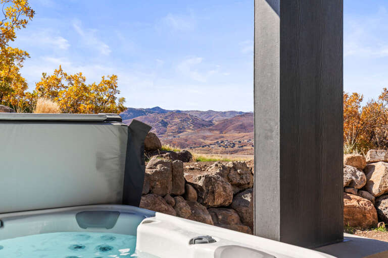 Soak in the bubbling hot tub as golden autumn leaves frame sweeping mountain vistas and peaceful valleys beyond the stone-edged terrace.