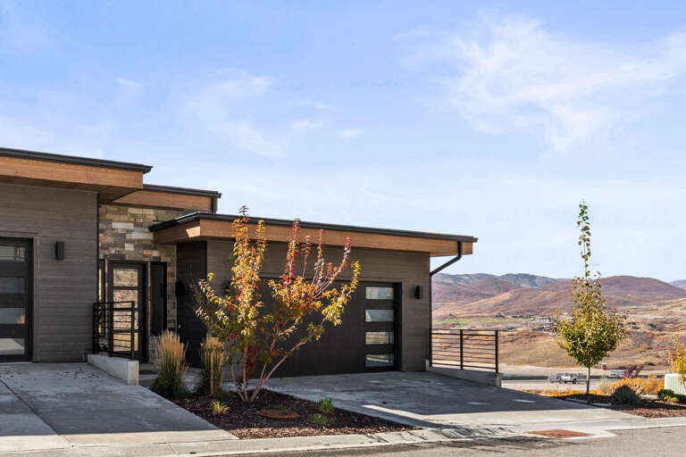 Modern architectural design nestled in striking high-desert terrain with distant mountain views and seasonal autumn foliage framing the entrance.