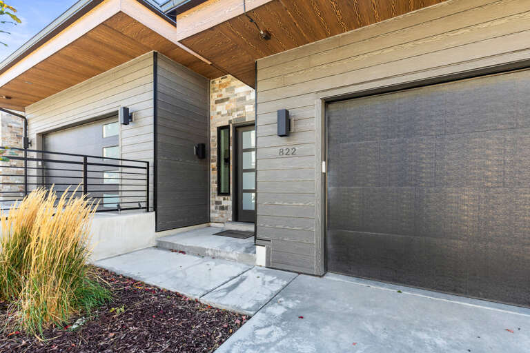Modern architecture greets visitors at this property entrance, featuring clean lines, mixed textures, and thoughtful landscaping that frames the inviting front door at unit 822.