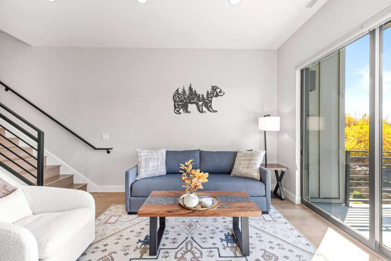 Unwind in your bright, modern living room with cozy seating, charming décor, and direct access to your private balcony overlooking golden autumn foliage.