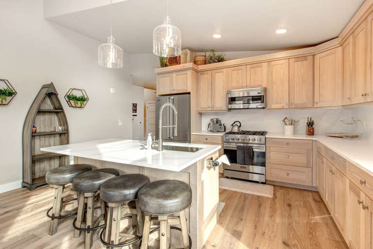 Mayflower Lakeside 1114-303: The fully equipped open kitchen has a central island with seating, light wood cabinets, and a modern tile backsplash with under-cabinet lighting. Mayflower Lakeside 1114-303: The fully equipped open kitchen has a central island with seating, light wood cabinets, and a modern tile backsplash with under-cabinet lighting.