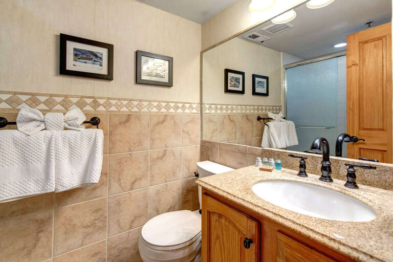 Step into your private bathroom featuring elegant tile work, granite countertops, and plush towels ready for your arrival—comfort and style await you here.