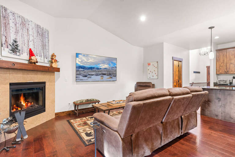 Sink into plush leather seating by your crackling fireplace, where mountain views on screen complement cozy evenings in this inviting living space.