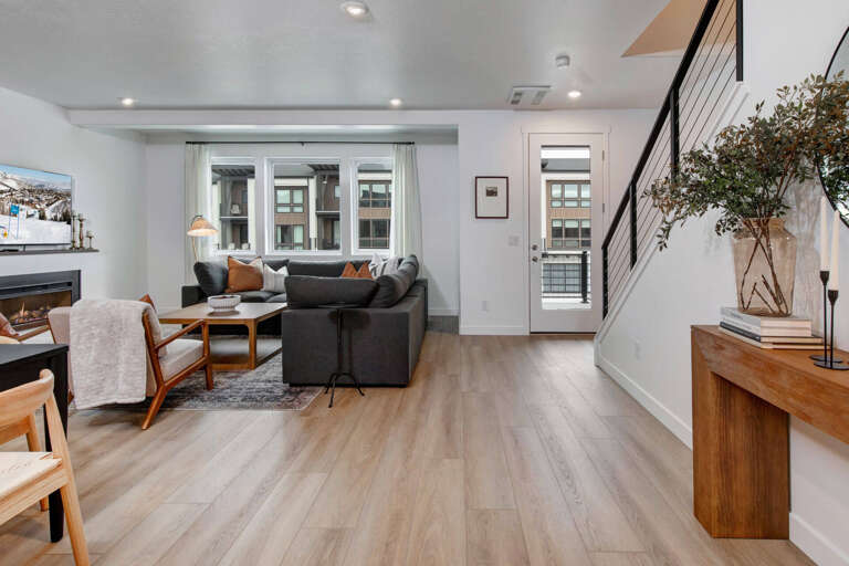 Step into your stylish living space featuring plush seating, warm wood accents, and natural light streaming through large windows.