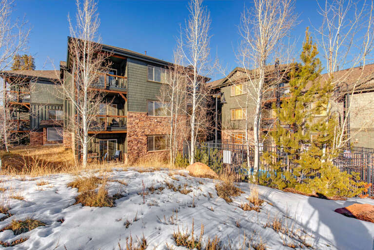 Mountain resort property set among snow-dusted natural landscape with neighboring condominiums and evergreen trees framing the area.