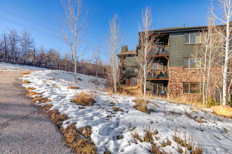 Mountain retreat surrounded by snow-covered landscape and bare winter trees under clear blue skies.