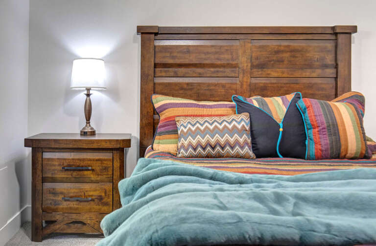 Sink into cozy comfort with this rustic wooden bed adorned with vibrant pillows and soft teal blanketsâyour perfect retreat awaits.