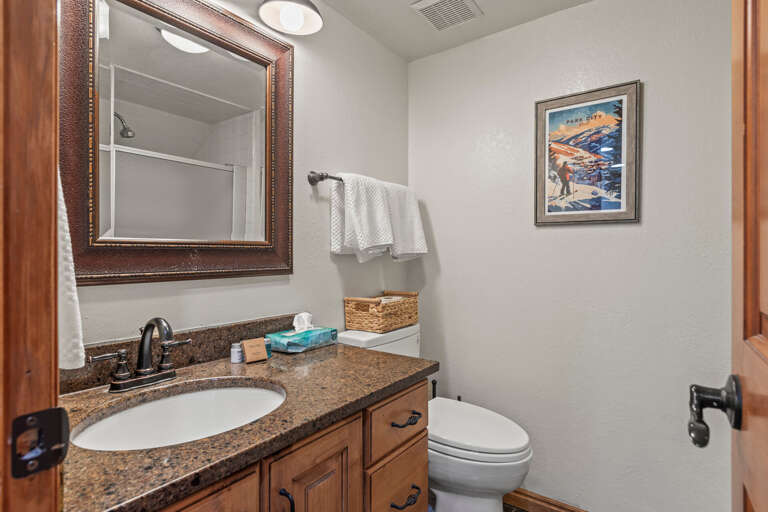 Your private bathroom features granite countertops, warm wood cabinetry, and fresh towels ready for your arrival.