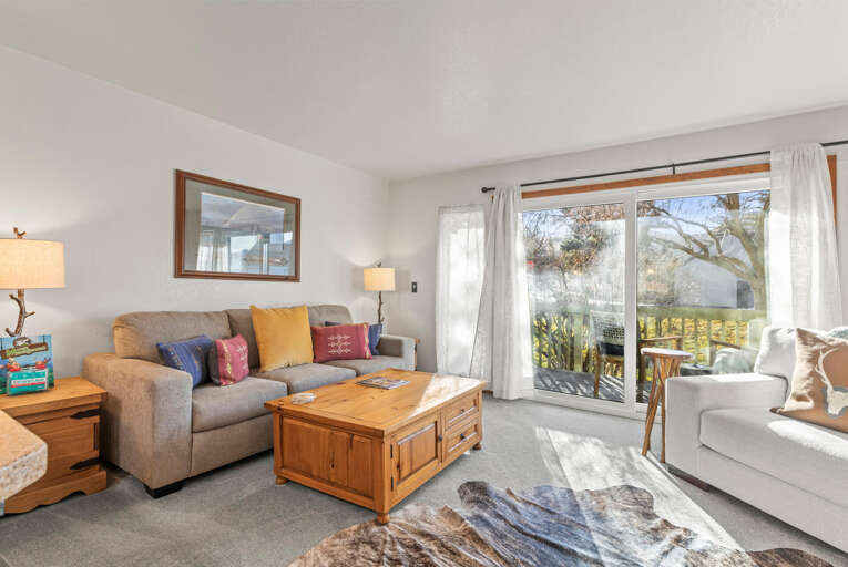 Sink into cozy comfort in your bright living room, where colorful pillows and warm wood accents create the perfect spot to unwind after exploring.