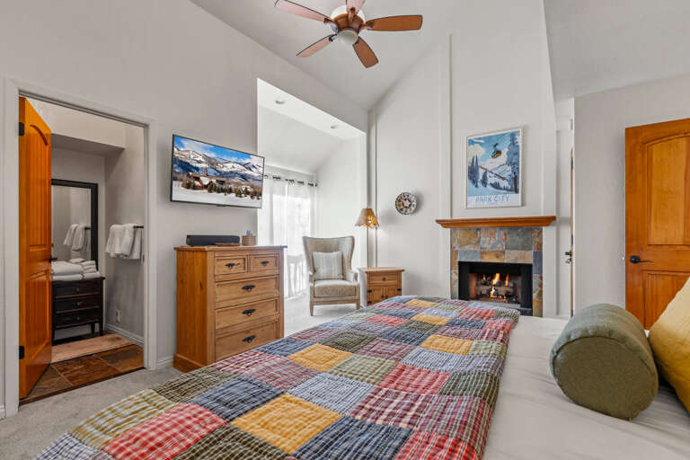 Unwind in your cozy bedroom with a crackling fireplace, soft quilted bedding, and charming mountain-themed decor that creates the perfect retreat.