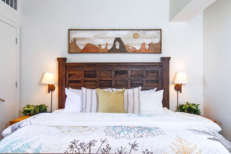 Sink into comfort in this serene bedroom with rustic wooden headboard, soft linens, and warm bedside lighting creating your perfect retreat.