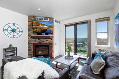 Unwind in your cozy living room with a crackling fireplace and stunning mountain views through the balcony doors.