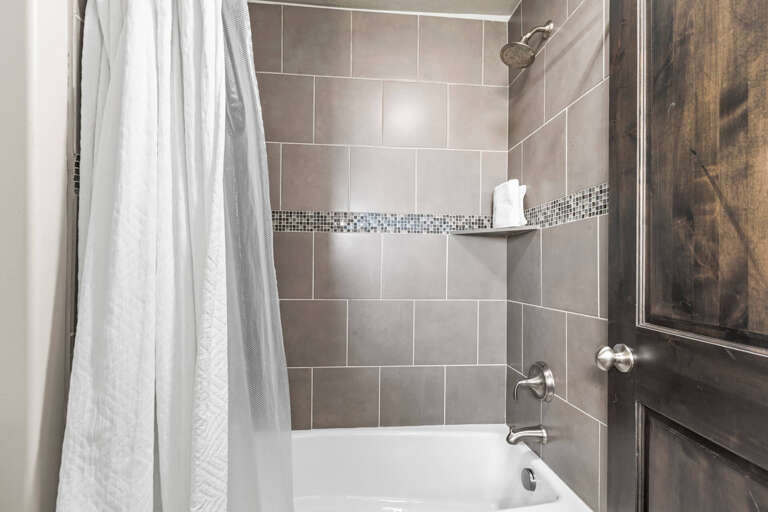 Your private bathroom features elegant gray tile with mosaic accents and a convenient built-in niche for toiletries.