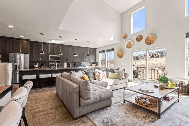 Relax in your open-concept living space featuring modern furnishings, a fully equipped kitchen, and stunning natural views through floor-to-ceiling windows.
