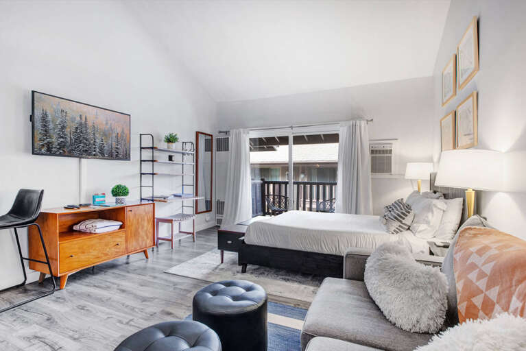 Relax in your stylish studio with modern furnishings, cozy seating, and natural light streaming through your private balcony doors.