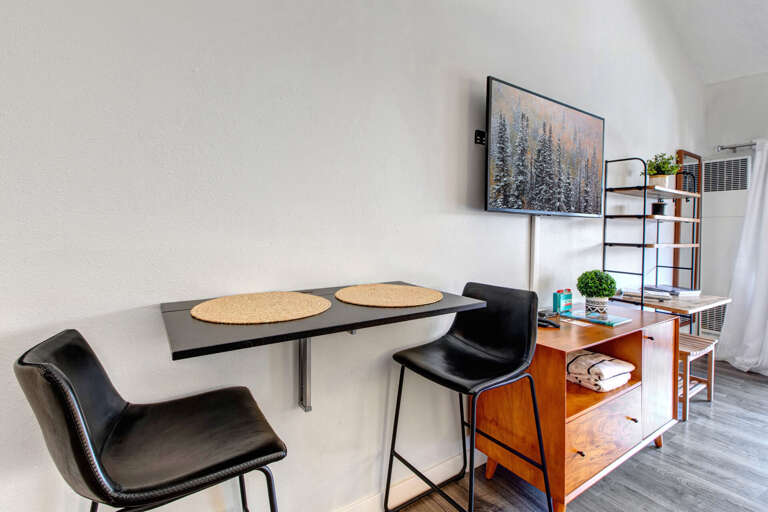Your sleek dining nook features modern black chairs and a stylish wall-mounted table, perfect for intimate meals or productive work sessions.