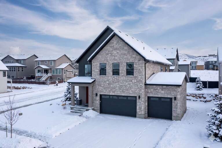 Modern stone-clad rental home situated in a quiet residential neighborhood, featuring two-car garage and mountain backdrop with convenient winter access.