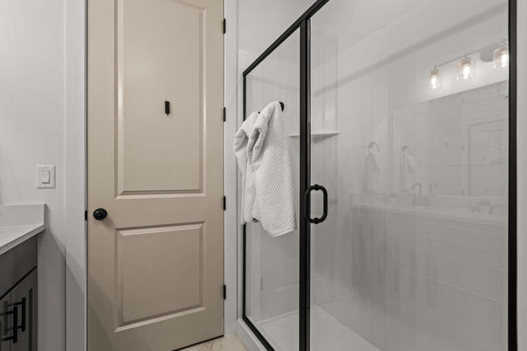 Crisp, modern bathroom awaits your arrival with a spacious walk-in shower, fresh white towels, and bright lighting—perfect for refreshing after a day of exploring.