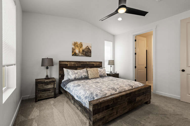 Slip into your serene bedroom retreat, where rustic wood tones meet modern comfort. A plush bed awaits under a sleek ceiling fan, with soft lighting and a peaceful ambiance perfect for restful nights.