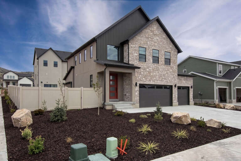 Modern two-story home featuring stunning stone and metal exterior with spacious three-car garage in peaceful neighborhood setting