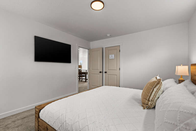 Sink into crisp white linens and unwind while watching your favorite shows on the mounted TV in this serene bedroom.