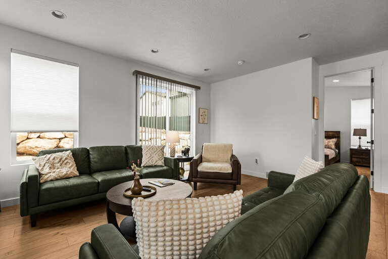 Sink into plush green leather sofas in your bright, modern living room with natural light streaming through large windows.