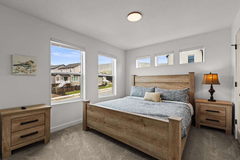 Unwind in your peaceful bedroom with rustic wood furniture, soft linens, and natural light streaming through multiple windows.