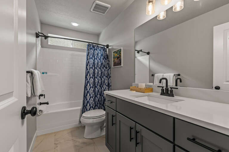 Unwind in your private, modern bathroom featuring a spacious tub, stylish fixtures, and a calming gray palette—perfect for refreshing after a day of exploration.