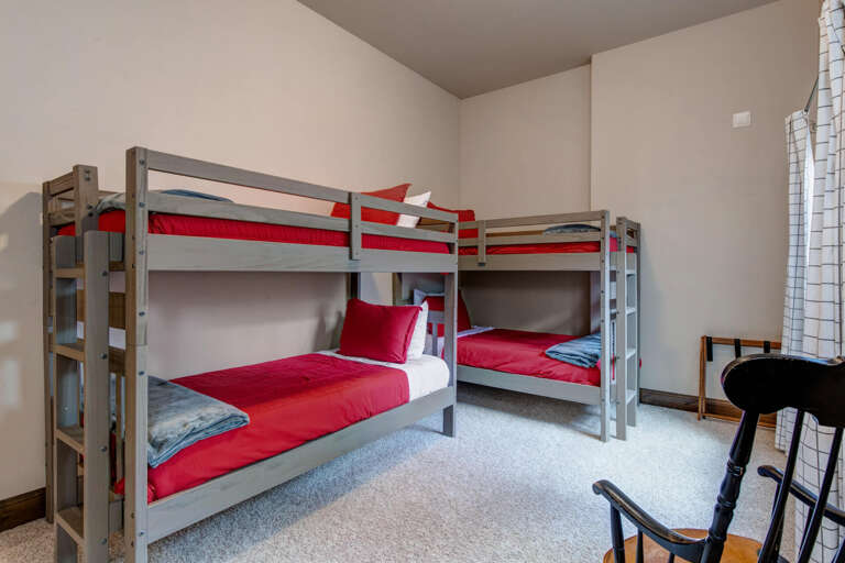 Perfect for families or groups, this room comfortably sleeps four with two sturdy bunk beds dressed in vibrant red linens. Clean, spacious, and ready for your mountain getaway.