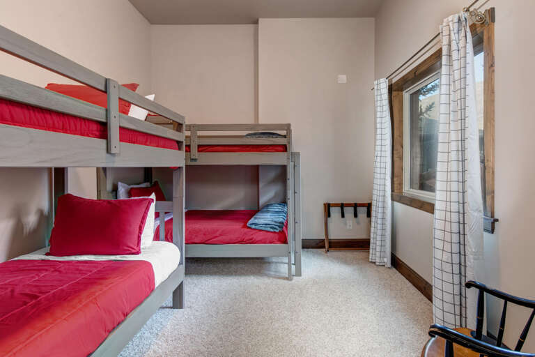 Your kids will love this cheerful bunk room with cozy red bedding and bright natural light streaming through the window. Perfect for creating fun vacation memories together.