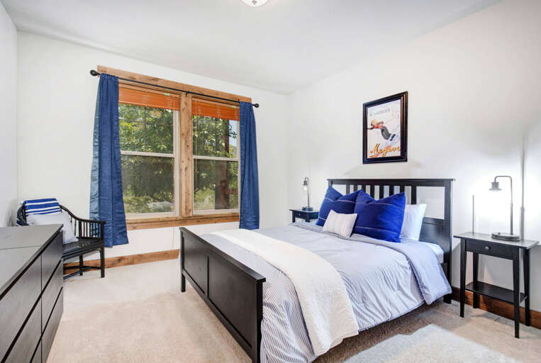 Step into your peaceful bedroom retreat, where crisp linens and layered pillows invite restful sleep. Natural light streams through the wood-framed window, while thoughtful furnishings create your own cozy sanctuary.