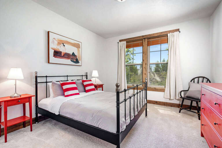 Rest easy in your cozy bedroom, where natural light streams through beautiful wooden-framed windows and reveals scenic views beyond. Crisp linens and cheerful pops of color create a welcoming retreat.