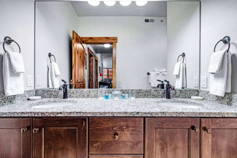 Freshen up at your private double-sink vanity, elegantly designed with granite countertops, rich wood cabinetry, and plush towels ready for you.