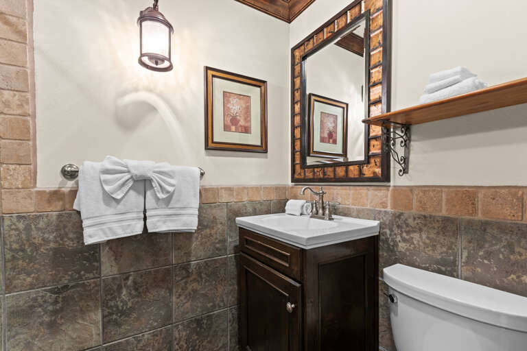 This charming bathroom features natural stone tile, a decorative wood-framed mirror, and plush towels waiting to refresh you after your day of adventure.