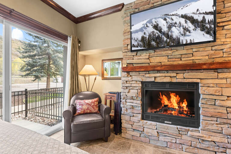 Cozy up in your chair by the crackling fireplace, with mountain views framing the window and a warm, inviting living space designed for your perfect alpine getaway.