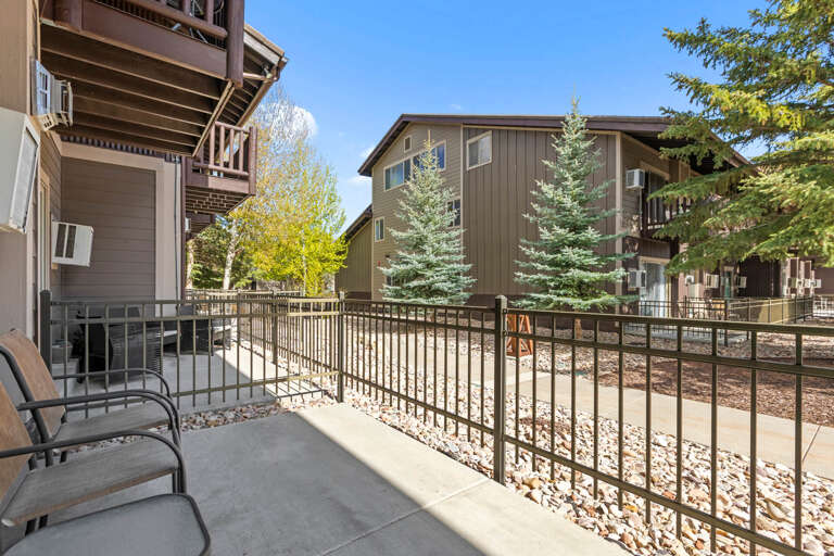 The property sits in a quiet, tree-lined neighborhood with evergreens and seasonal foliage framing the arrival experience.