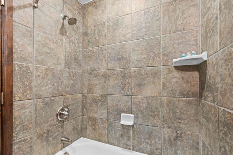 Step into your private sanctuary featuring elegant stone-tiled walls and a refreshing tub-shower combo, ready for unwinding after a day of exploring.