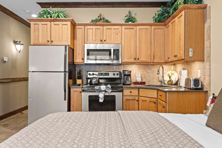 Your suite features a fully equipped kitchen with stainless steel appliances, wood cabinetry, and granite countertops, perfect for preparing home-cooked meals during your stay.