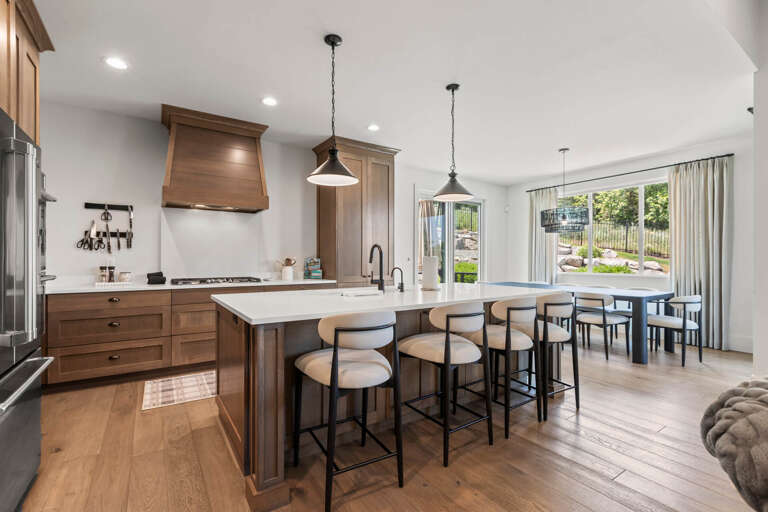 Step into your open-concept kitchen featuring warm wood cabinetry, quartz countertops, and an inviting island with bar seatingâperfect for morning coffee or meal prep while chatting with friends and family.