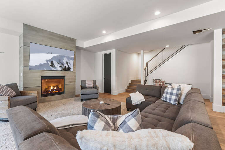Unwind in this inviting downstairs living space, where plush seating surrounds a warm fireplace. Sink into comfortable sofas, enjoy your favorite shows on the mounted TV, and let the cozy ambiance welcome you home.