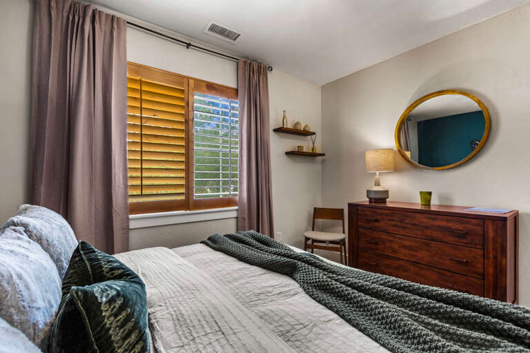 Your peaceful retreat awaits with a plush bed, elegant wood furnishings, and soft natural light streaming through plantation shuttersâperfect for unwinding after your adventures.