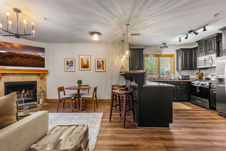Relax in your beautifully appointed open-plan living space, where warm wood floors, elegant cabinetry, and a cozy fireplace create the perfect setting for unwinding after a day of mountain adventures.