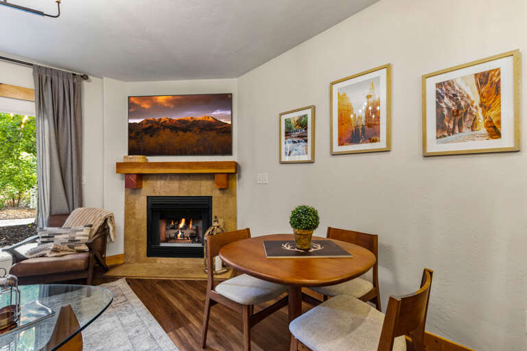 Relax by the cozy fireplace in your inviting living space, where stunning mountain artwork and natural light create a warm, welcoming atmosphere for your stay.