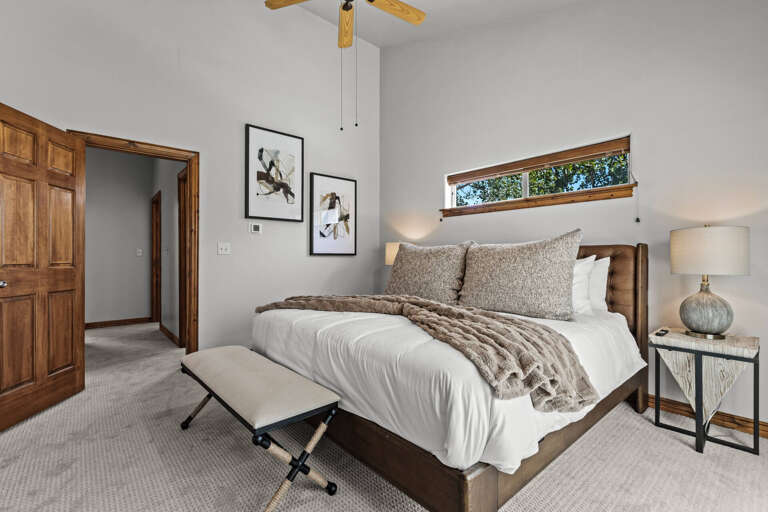 Your serene bedroom retreat features warm wood accents, plush linens, and a cozy throw blanket that invites you to unwind after a day of mountain adventures.