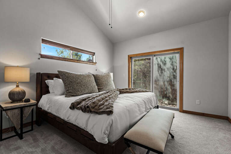 Wake up refreshed in this peaceful bedroom with plush bedding, warm wood accents, and natural light streaming through your private window. The sliding door opens to the outdoors, blending comfort with nature.