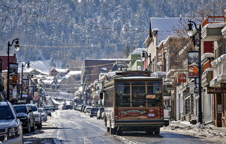 A charming winter street scene featuring colorful buildings, festive lights, and snow-dusted mountains, framing the property's picturesque neighborhood and access to local shops and transportation.