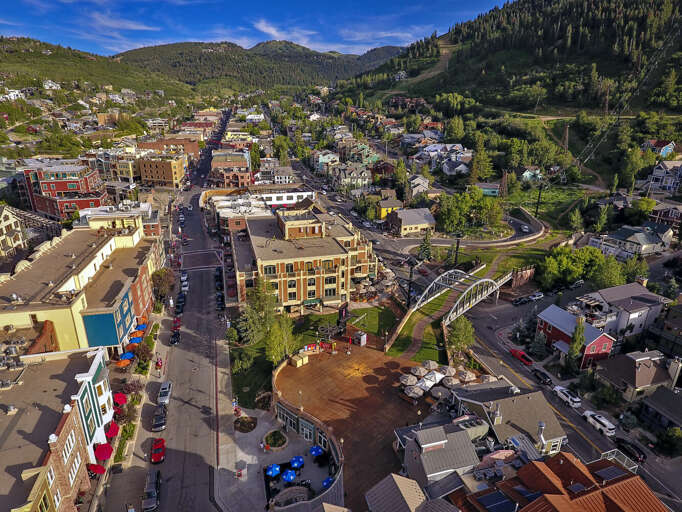 Aerial view of the mountain town and surrounding neighborhood, showcasing the property's location within a scenic alpine community framed by forested peaks and hillside homes.